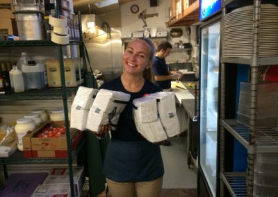 Moby Dick's restaurant staff member smiling while holding packages of napkins