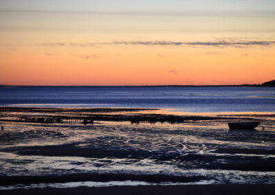 view of bay at low tide with orange sky